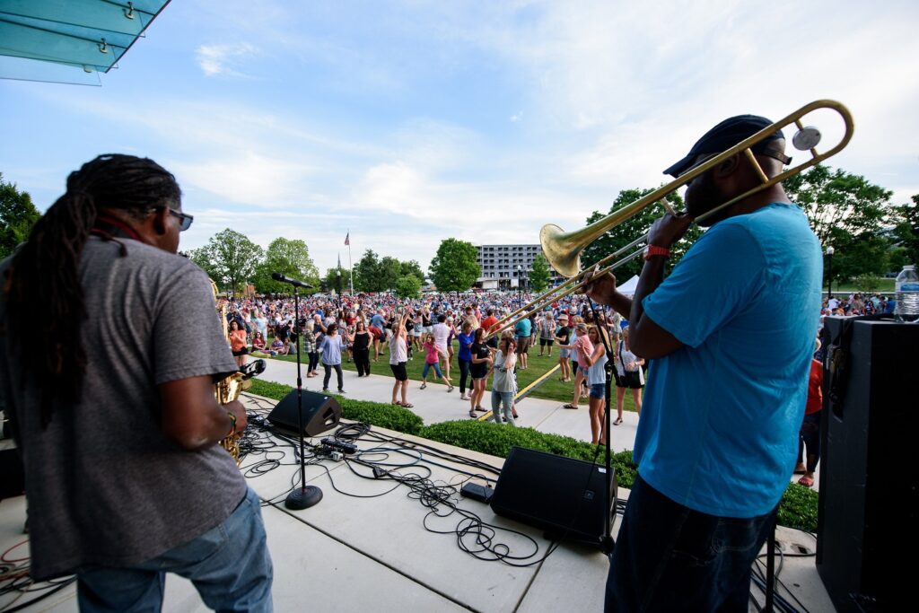 band playing on an outdoor stage and people dancing in the audience