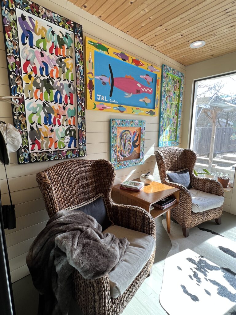 colorful art on the wall above chairs in a sunroom