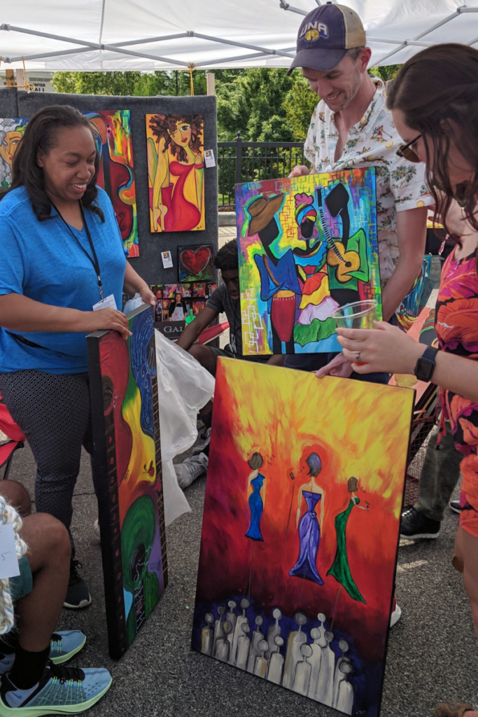 Artist selling colorful paintings at an art market