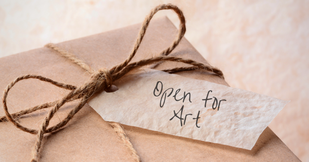 a brown paper wrapped gift with a twine bow and card that reads open for art