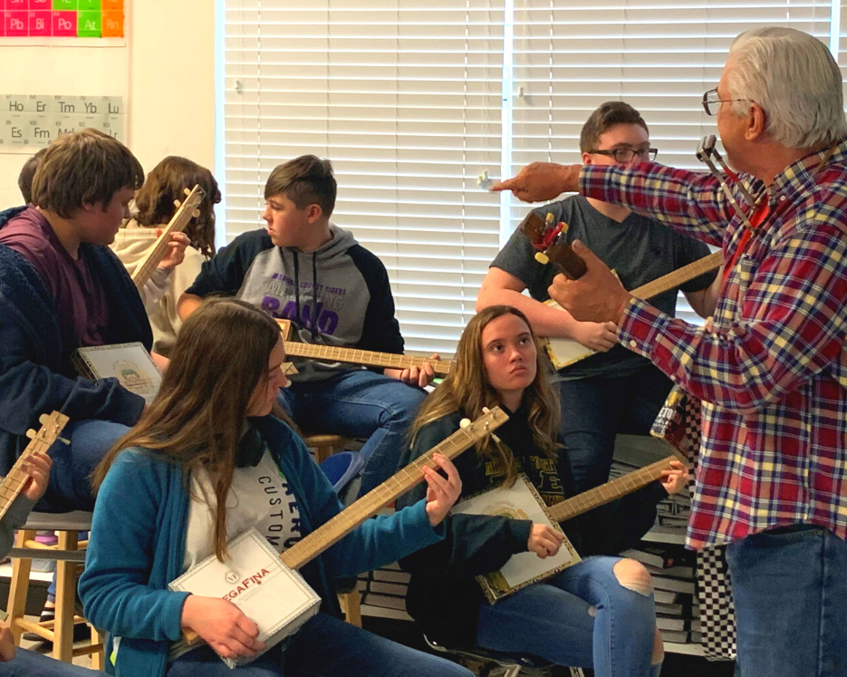 instructor and students who have made cigar box guitars and are learning how to play them