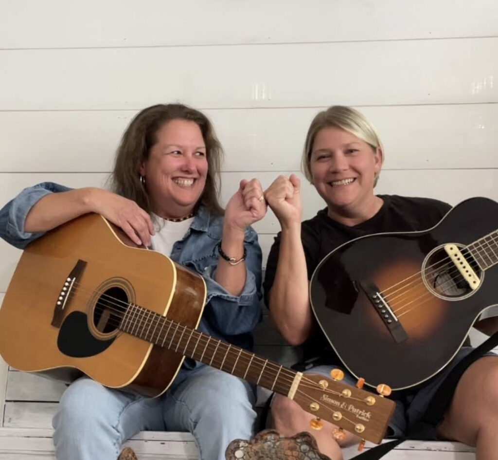 Christy & Alli holding their guitars and fist bumping