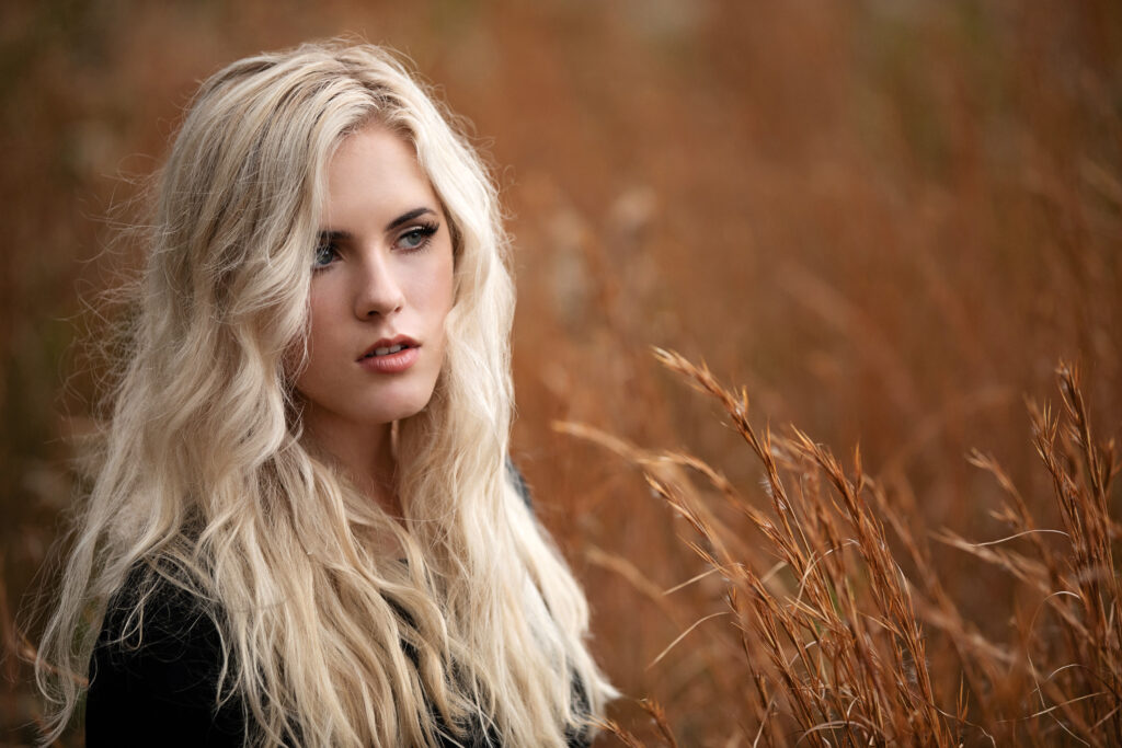 Delaney Faulds professional photo sitting in a field of wheat