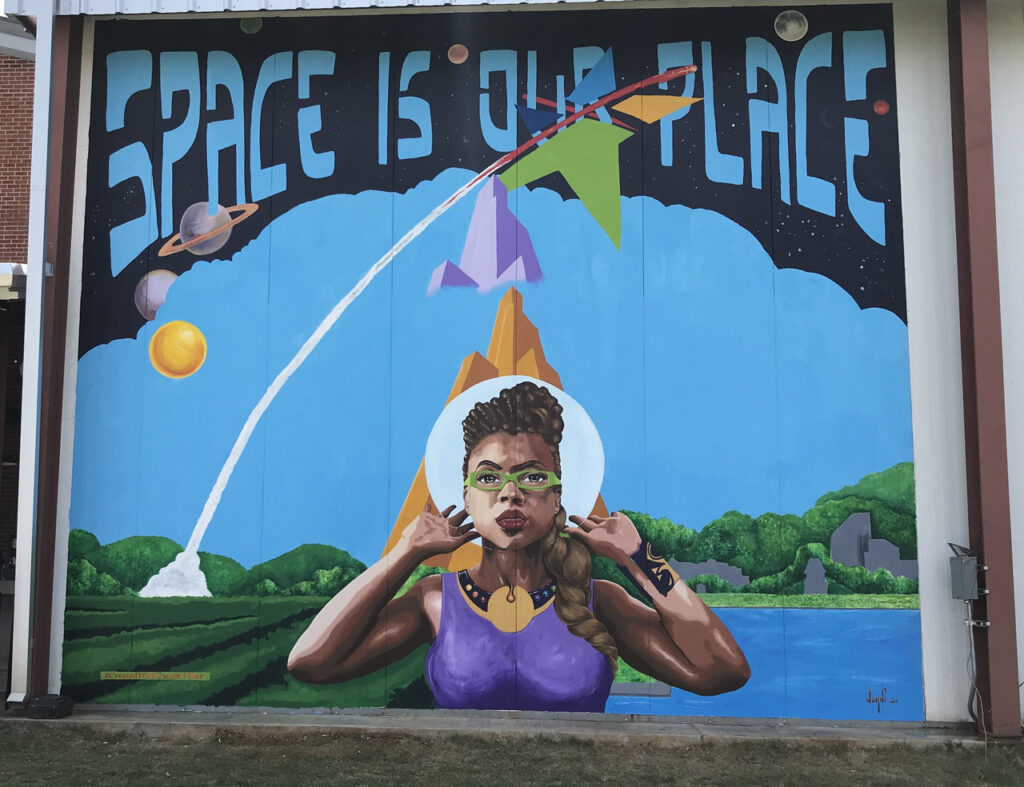 A mural of a female astronaut that reads 'Space is Our Place'