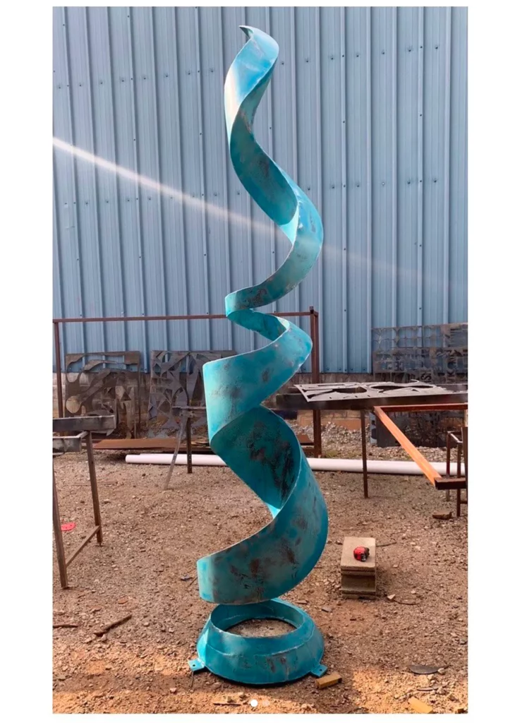 An abstract teal-colored metal spiral, outdoor sculpture.