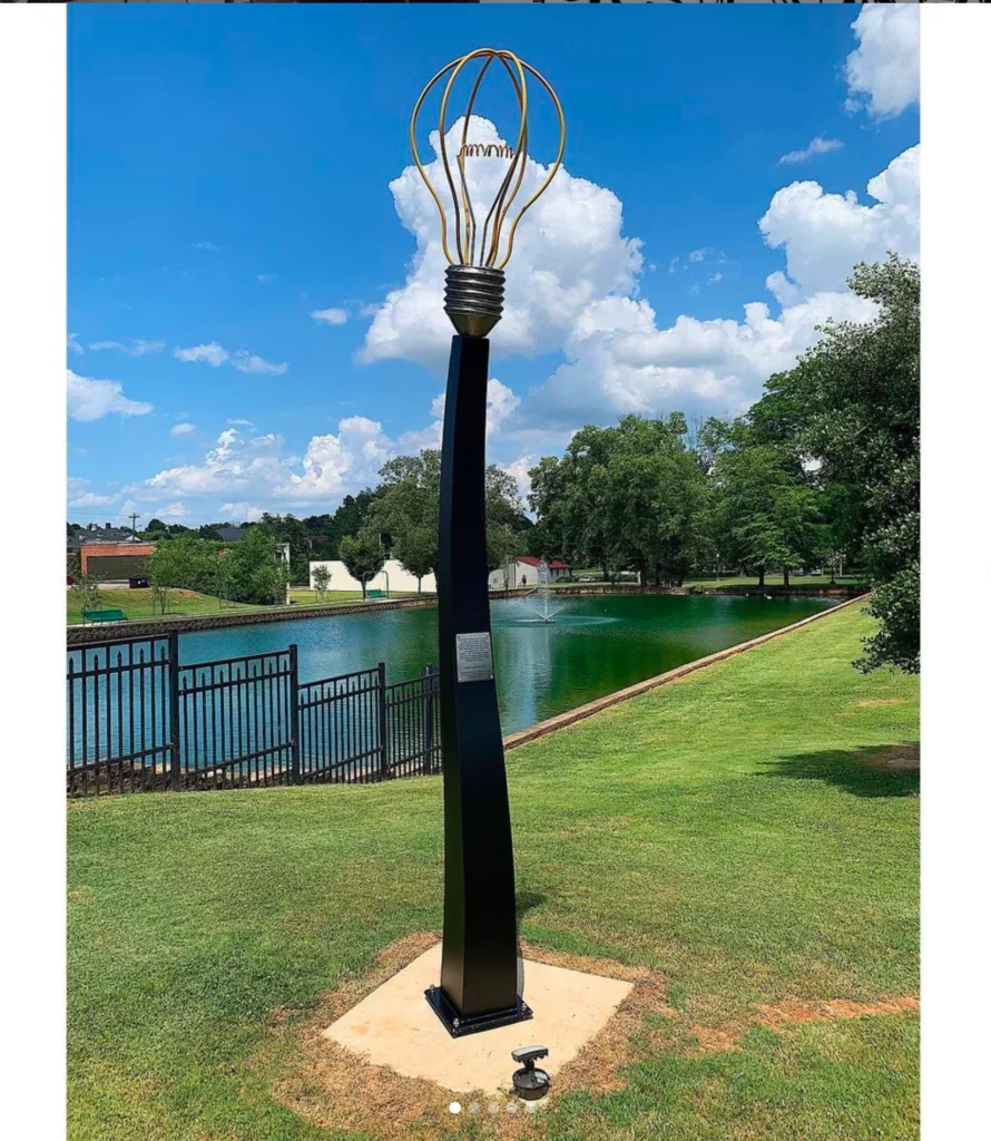 An outdoor sculpture, metal light bulb on a plinth.