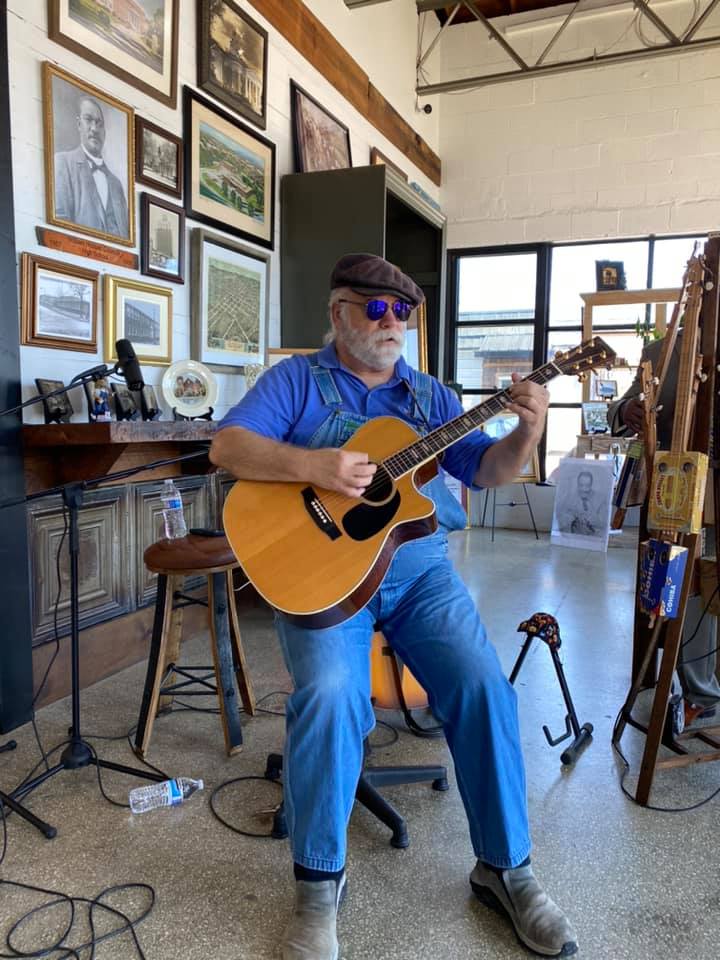 Man playing acoustic guitar sitting on a stool