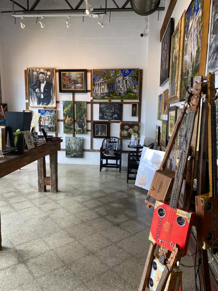 looking across a room at a small art gallery wall with cigar box guitars visible