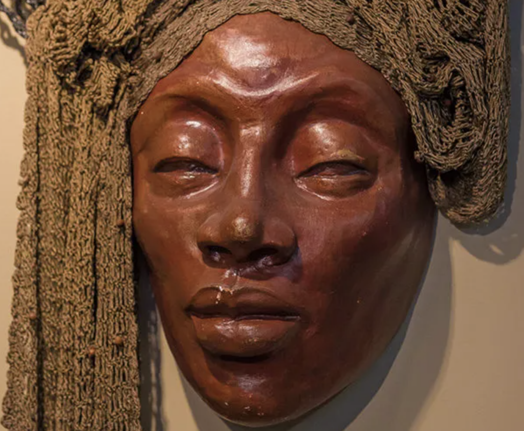 Sculpture of a face draped with textile.